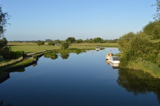 A wide, peaceful river with a few boats on it.
